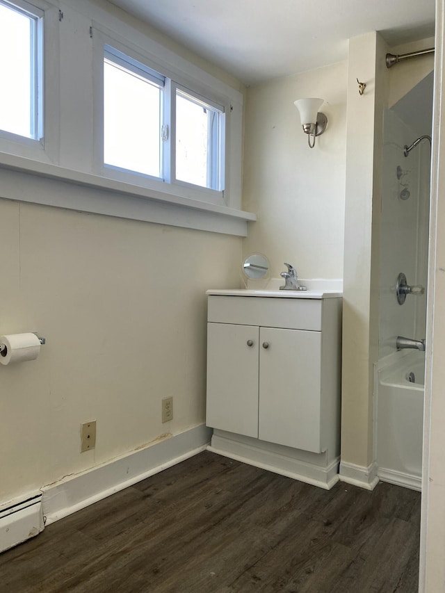 bathroom with hardwood / wood-style flooring, shower / bathtub combination, vanity, and baseboard heating