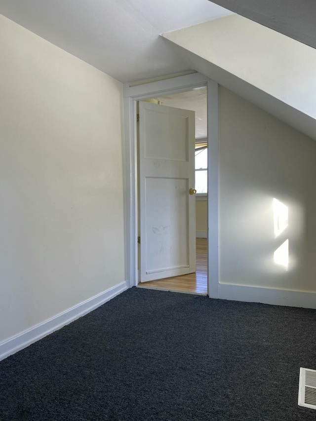 additional living space with carpet floors and vaulted ceiling