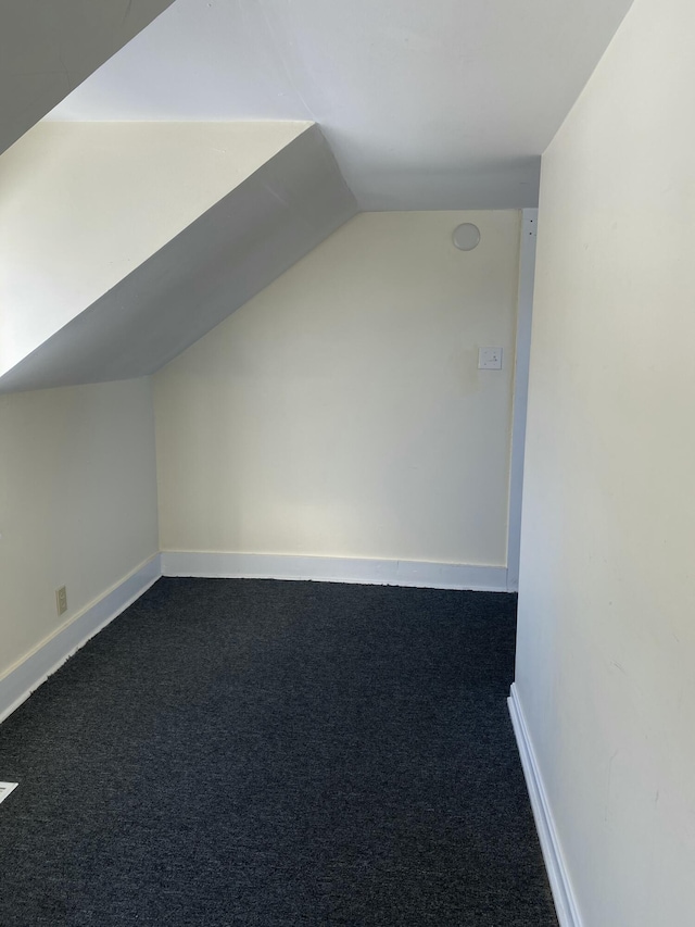 additional living space featuring lofted ceiling and dark carpet