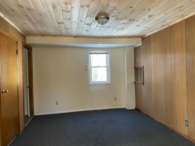 carpeted spare room featuring wood ceiling and wood walls