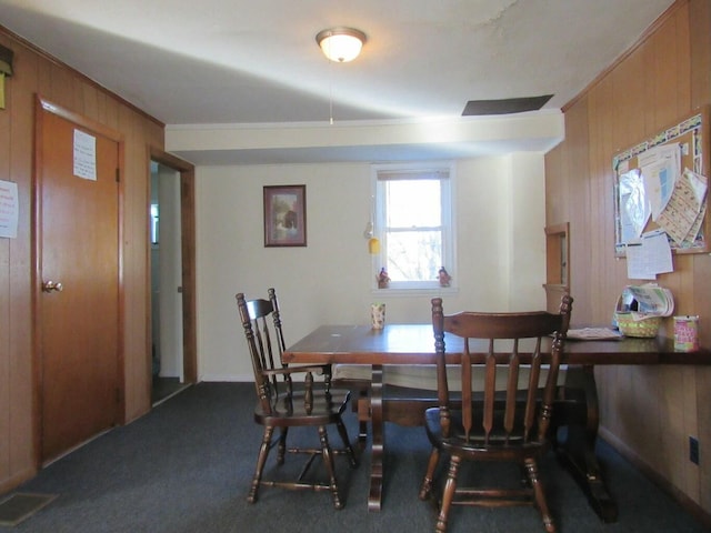 carpeted dining room featuring wooden walls