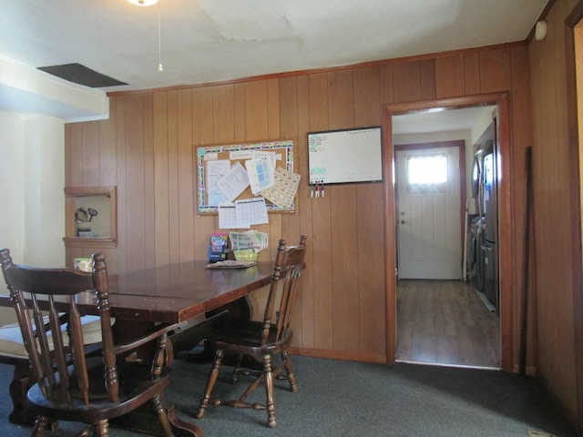 dining area featuring dark carpet and wood walls