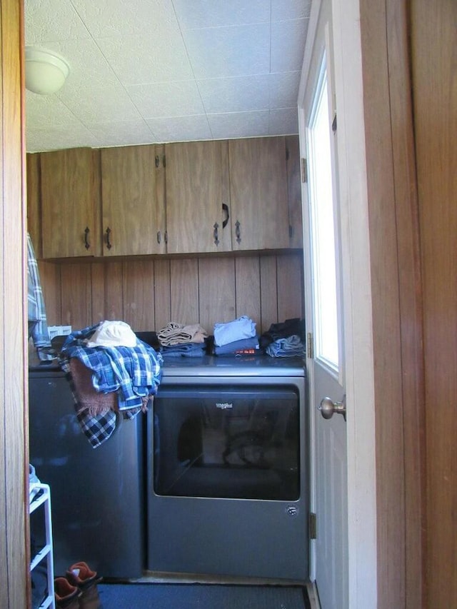 laundry room with washer / dryer, cabinets, and wood walls