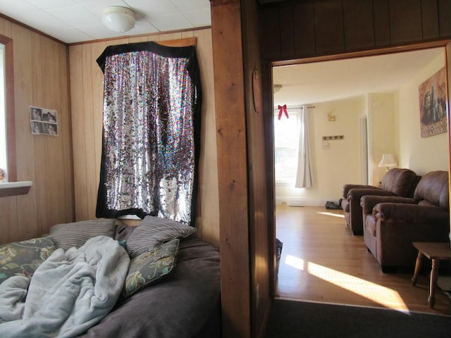 bedroom featuring light hardwood / wood-style flooring, ornamental molding, and wooden walls