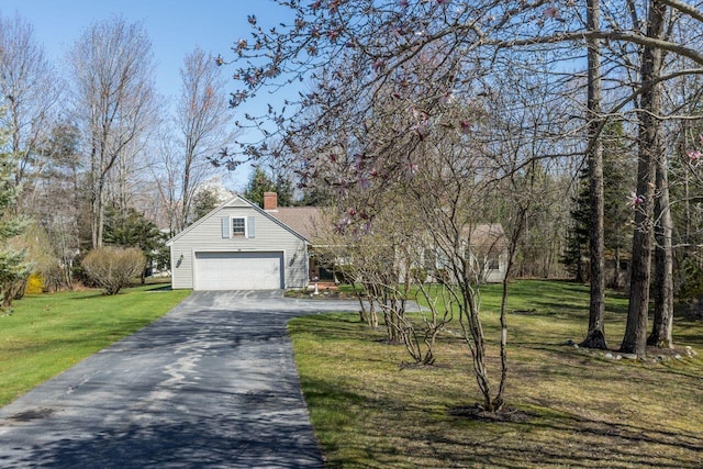 exterior space with a garage, a chimney, a lawn, and aphalt driveway