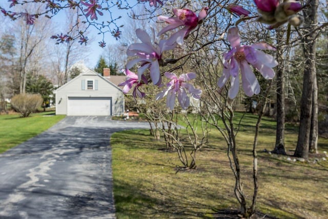 view of front of house with a garage, a chimney, driveway, and a front yard