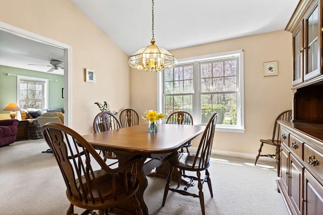 dining room with baseboards, ceiling fan with notable chandelier, lofted ceiling, and light carpet
