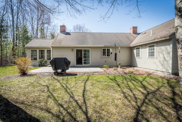 rear view of house with a lawn, a chimney, and a patio area