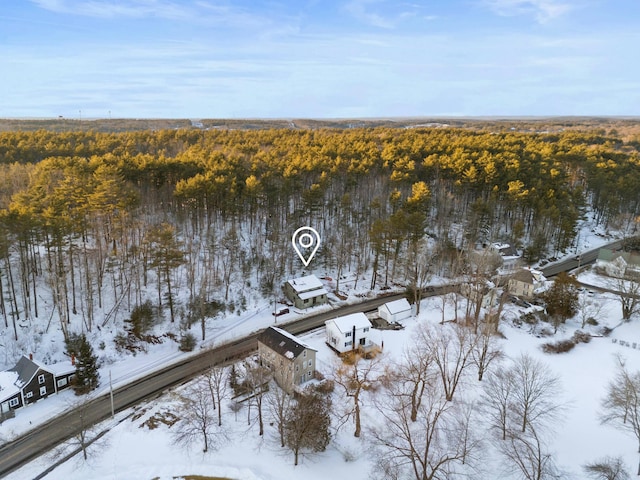 snowy aerial view featuring a wooded view