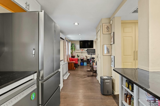 kitchen featuring dark wood-style flooring, recessed lighting, visible vents, freestanding refrigerator, and dark stone countertops