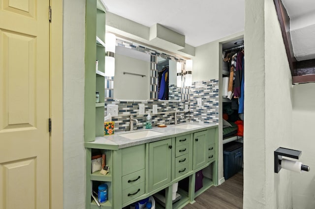 bathroom with double vanity, wood finished floors, backsplash, and a sink