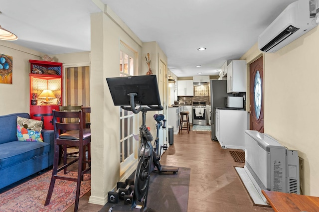 exercise area featuring an AC wall unit, dark wood-type flooring, and recessed lighting