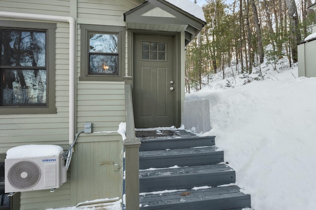 snow covered property entrance with ac unit