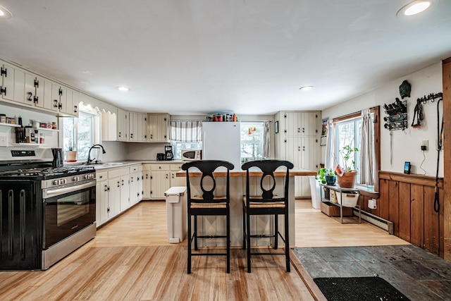 kitchen featuring white cabinetry, sink, white appliances, and light hardwood / wood-style flooring