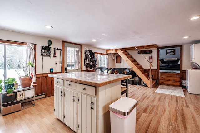 kitchen with tile countertops, light hardwood / wood-style floors, washer / clothes dryer, and white cabinets