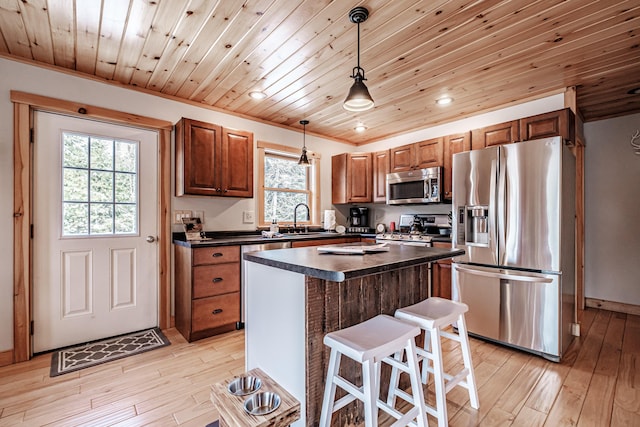 kitchen featuring decorative light fixtures, stainless steel appliances, light hardwood / wood-style floors, and a kitchen island