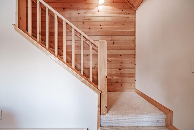 stairs featuring carpet flooring and wooden walls