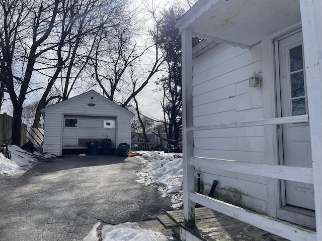 view of side of home featuring driveway, an outdoor structure, and a detached garage