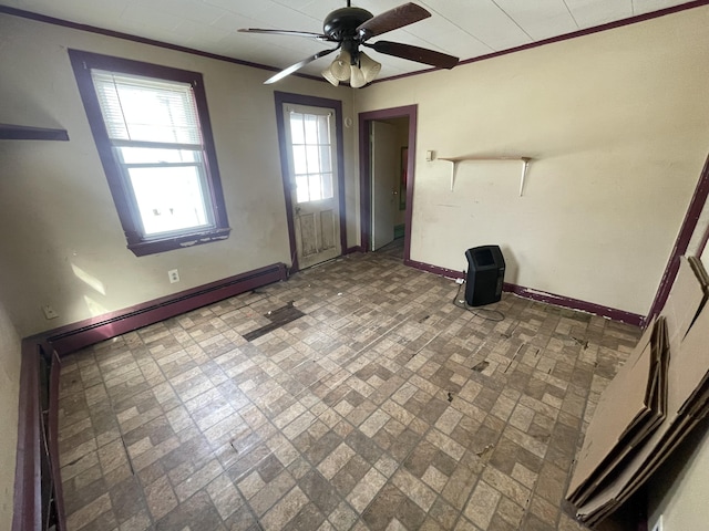 interior space with brick floor, baseboard heating, ornamental molding, a ceiling fan, and baseboards