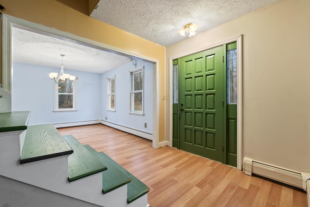 entryway with a notable chandelier, wood-type flooring, a baseboard radiator, and a textured ceiling