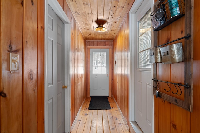 doorway with wood ceiling, light hardwood / wood-style flooring, and wooden walls