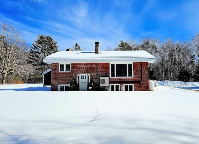 snow covered house with a chimney and brick siding