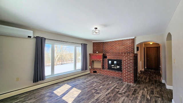 unfurnished living room featuring arched walkways, baseboard heating, dark wood-type flooring, a brick fireplace, and an AC wall unit