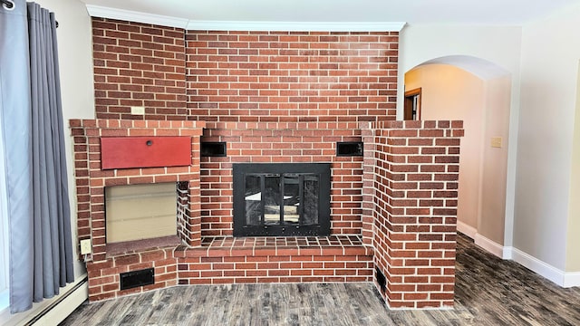 unfurnished living room with dark wood-style floors, crown molding, baseboard heating, a brick fireplace, and baseboards