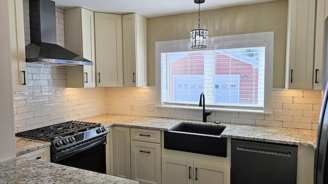 kitchen featuring decorative light fixtures, wall chimney exhaust hood, a sink, light stone countertops, and black appliances