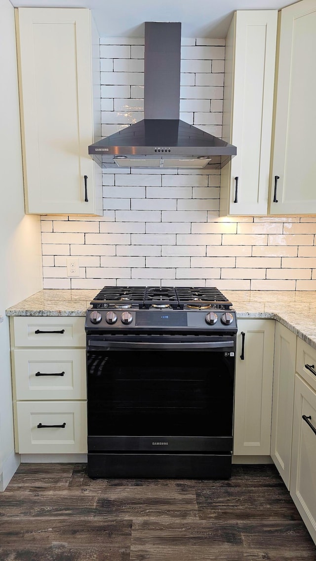 kitchen with light stone counters, dark wood-style flooring, white cabinetry, wall chimney exhaust hood, and gas stove