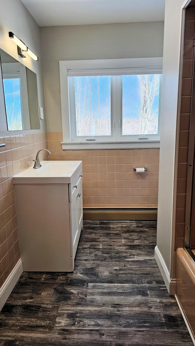 full bathroom featuring a healthy amount of sunlight, tile walls, wood finished floors, and vanity