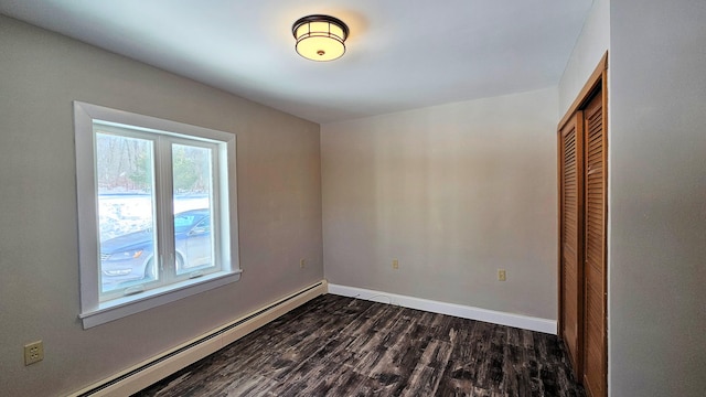 spare room with dark wood-style floors, baseboards, and baseboard heating