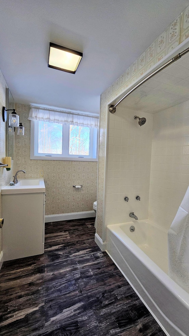 full bathroom with vanity, shower / tub combination, wood finished floors, baseboards, and wallpapered walls