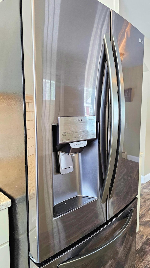 interior details with stainless steel fridge, baseboards, light countertops, and wood finished floors