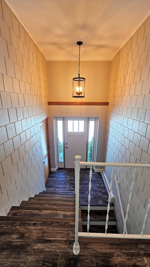 foyer entrance featuring an inviting chandelier, a baseboard radiator, dark wood-style flooring, and tile walls