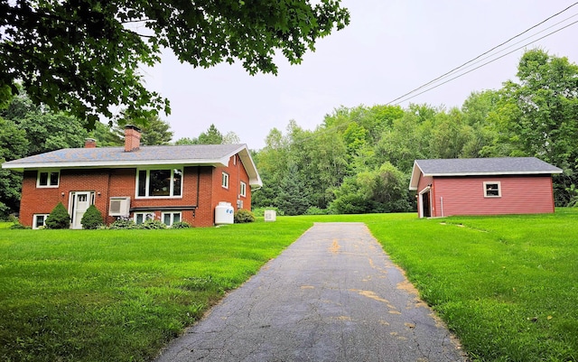 view of property exterior featuring a yard, aphalt driveway, a chimney, and brick siding