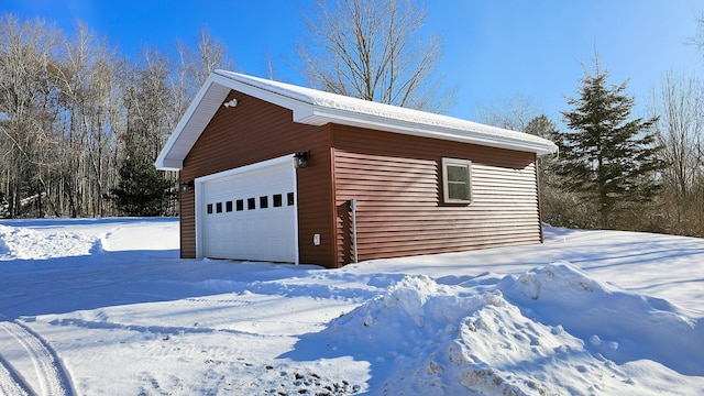 snow covered garage featuring a detached garage