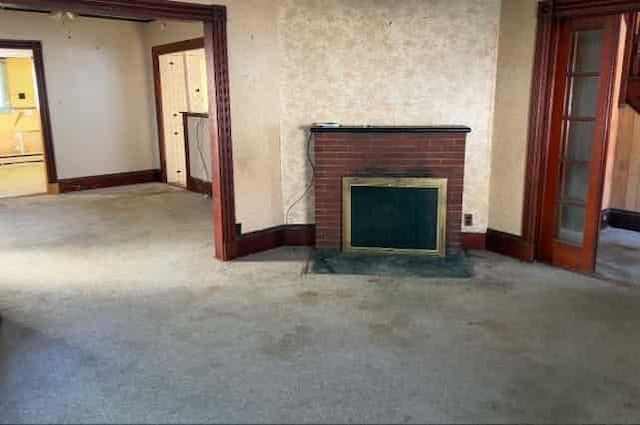 unfurnished living room featuring carpet floors, a fireplace, and baseboard heating