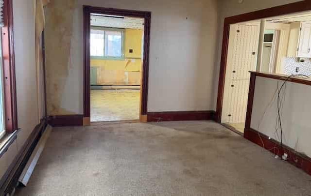 empty room featuring a baseboard radiator and carpet flooring