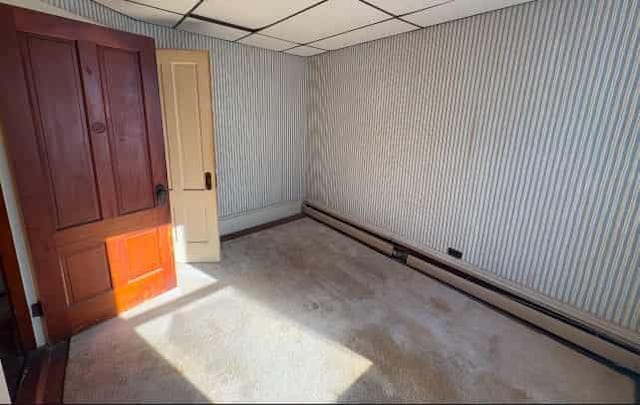 spare room featuring baseboard heating and a paneled ceiling