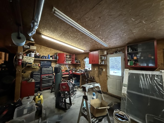 miscellaneous room featuring lofted ceiling, concrete flooring, and a workshop area