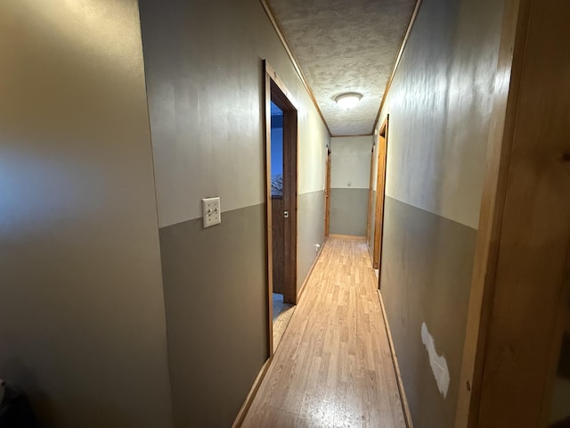 corridor with a textured ceiling and light wood-type flooring