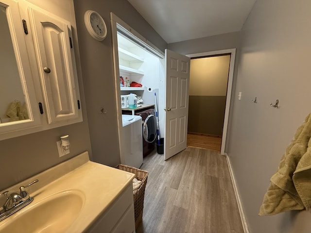 bathroom featuring hardwood / wood-style flooring, washer and clothes dryer, and sink