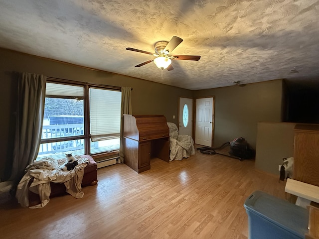 interior space with ceiling fan, a baseboard radiator, a textured ceiling, and light wood-type flooring