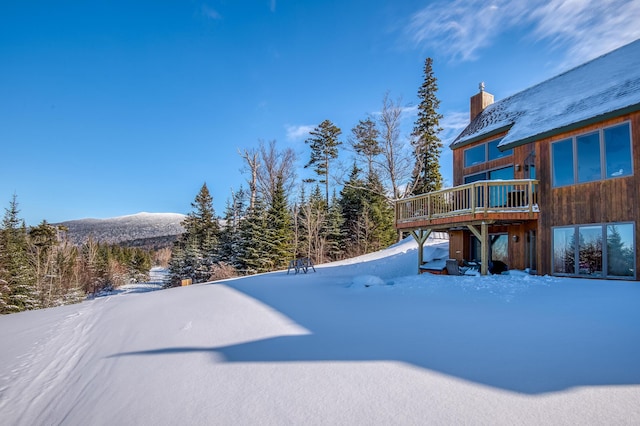 yard layered in snow featuring a deck with mountain view