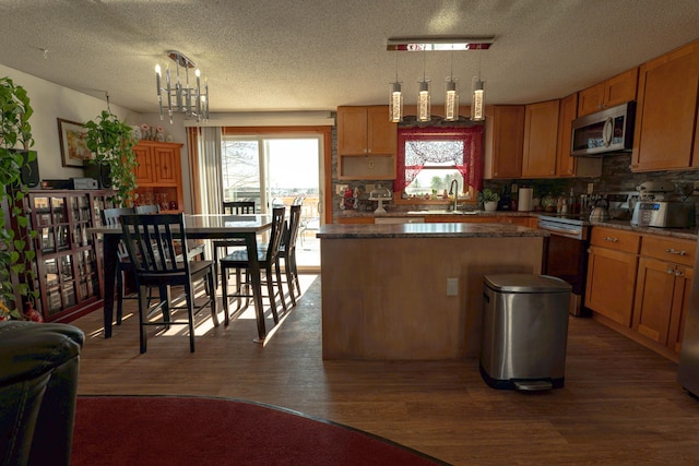 kitchen featuring plenty of natural light, appliances with stainless steel finishes, and decorative light fixtures