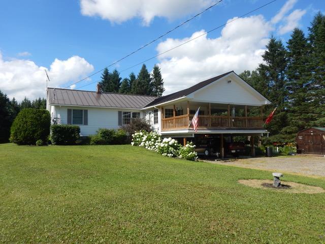 rear view of house featuring a yard, covered porch, and a shed