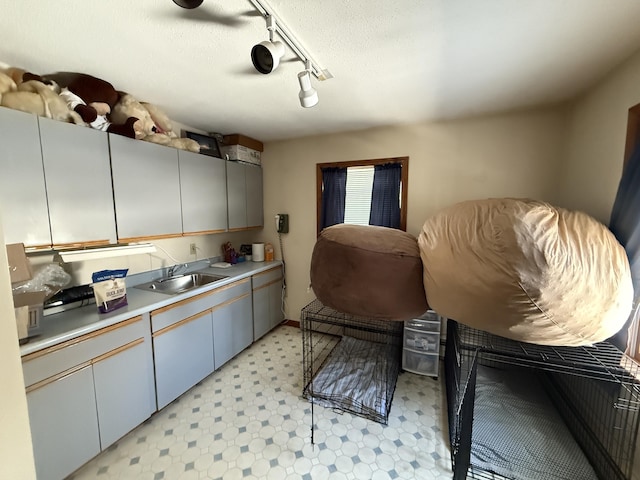 kitchen featuring rail lighting, sink, and a textured ceiling