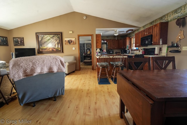 dining area featuring ceiling fan, lofted ceiling, and light wood-type flooring