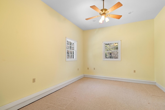 carpeted spare room with ceiling fan and baseboards